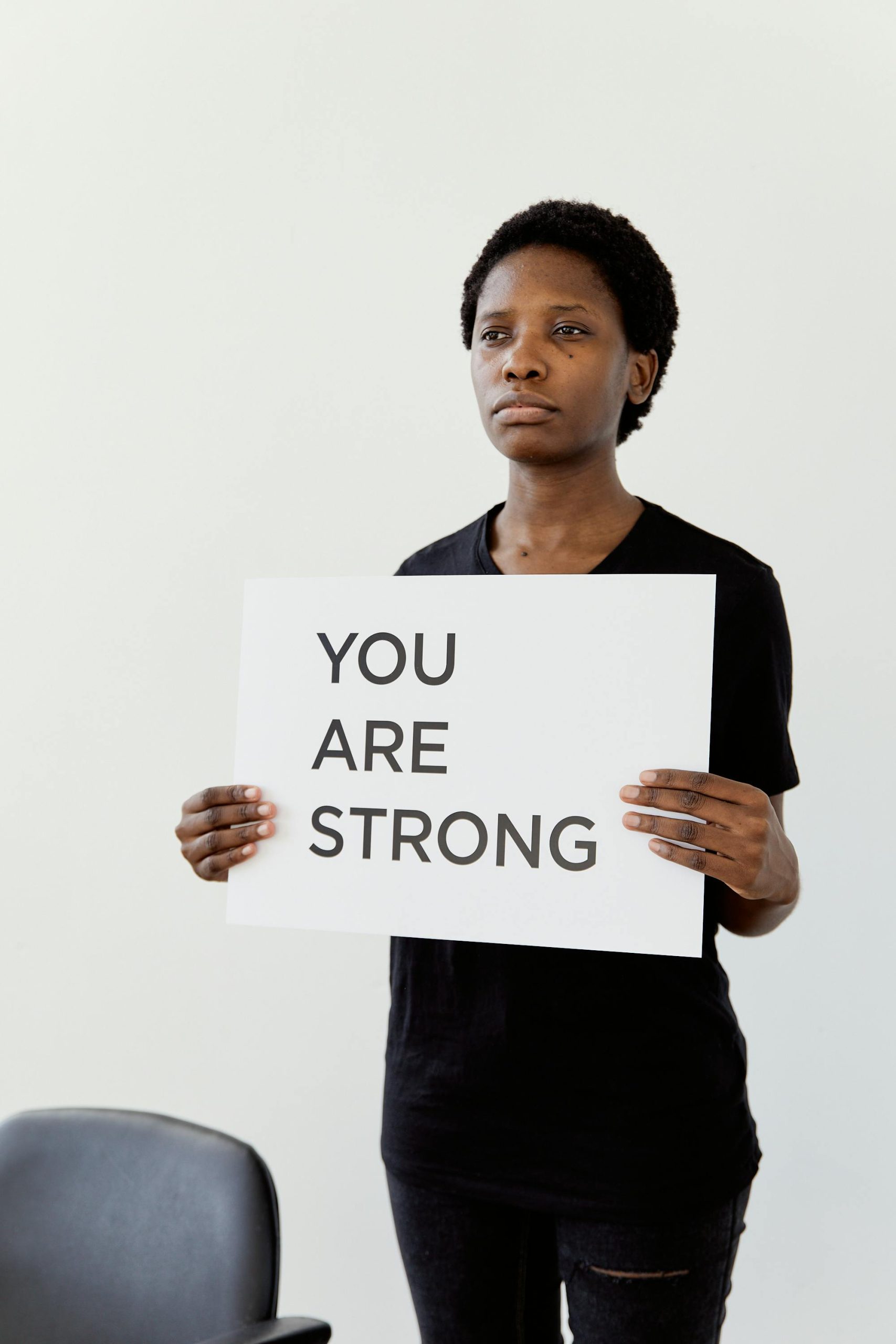 A person holds a 'YOU ARE STRONG' sign, promoting empowerment and resilience.